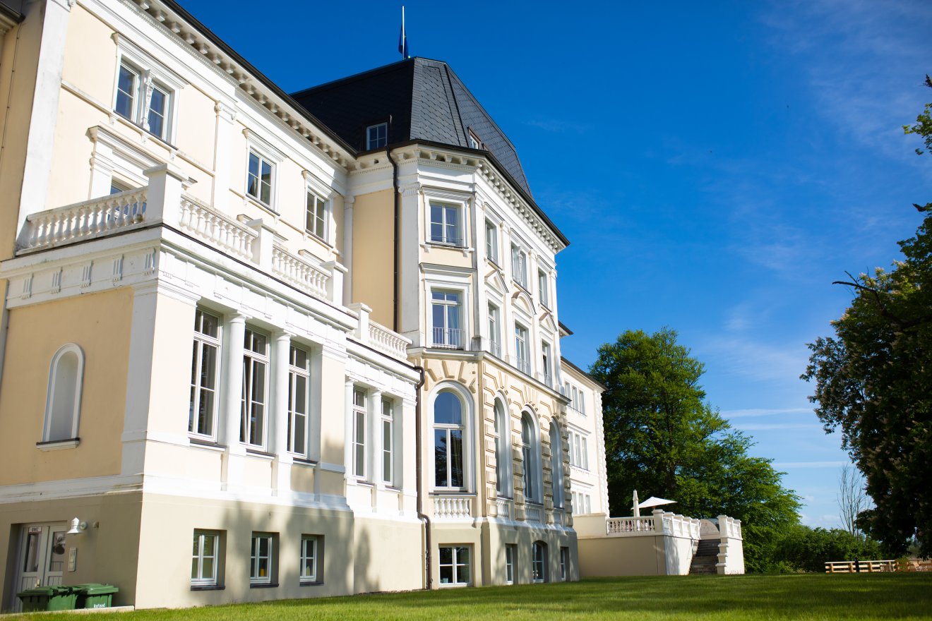 Schloss Lütgenhof – Seitenansicht mit Parkanlage unter blauem Himmel