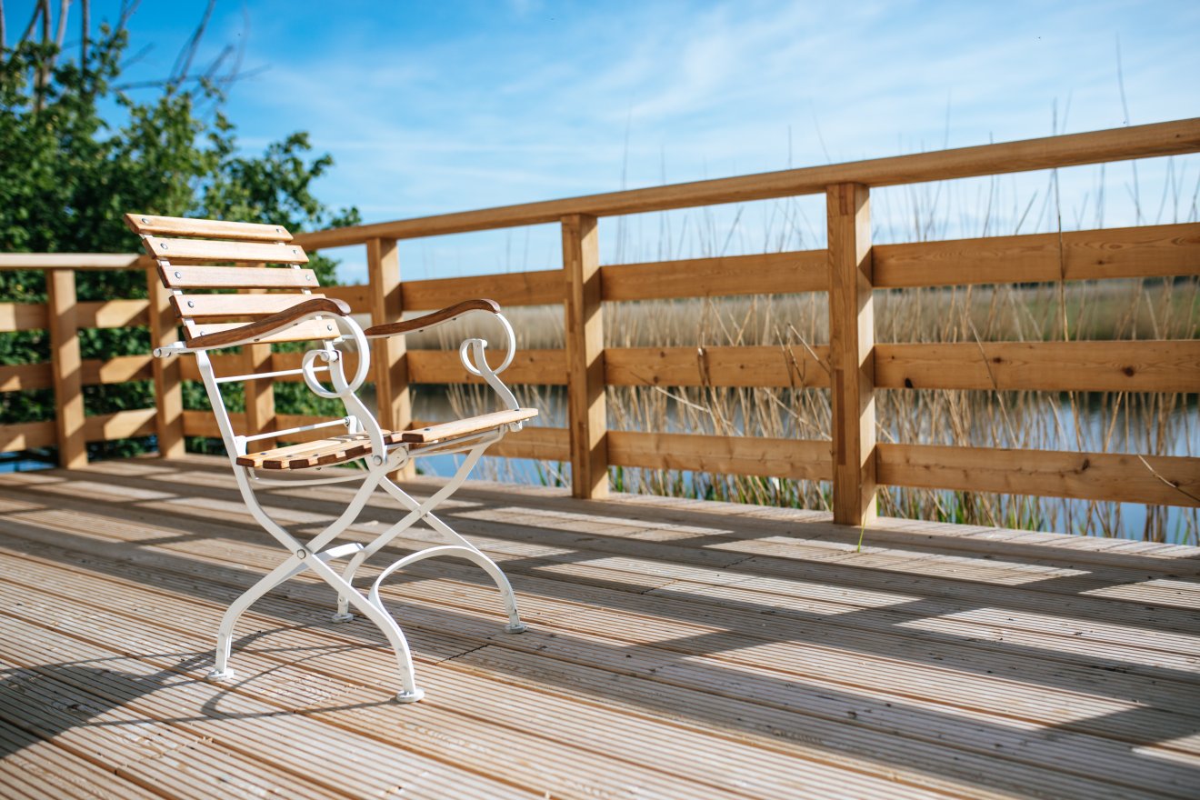 Ruhiger Sitzplatz auf der Holzterrasse am Wasser im Park des Klinikum Schloss Lütgenhof