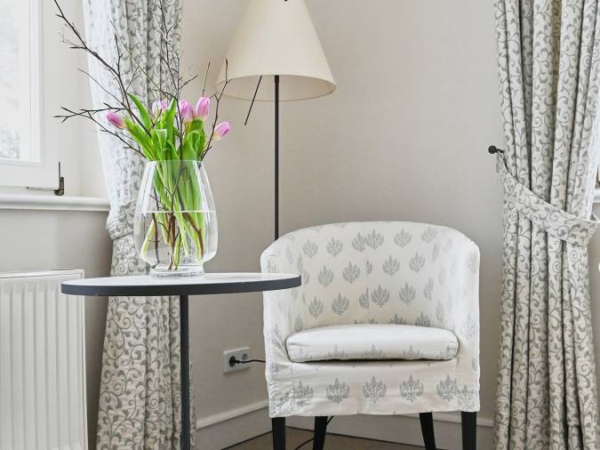 Ein helles Wohnzimmer, das einen Stuhl und eine Vase auf dem Tisch zeigt, ideal für entspannte Momente.