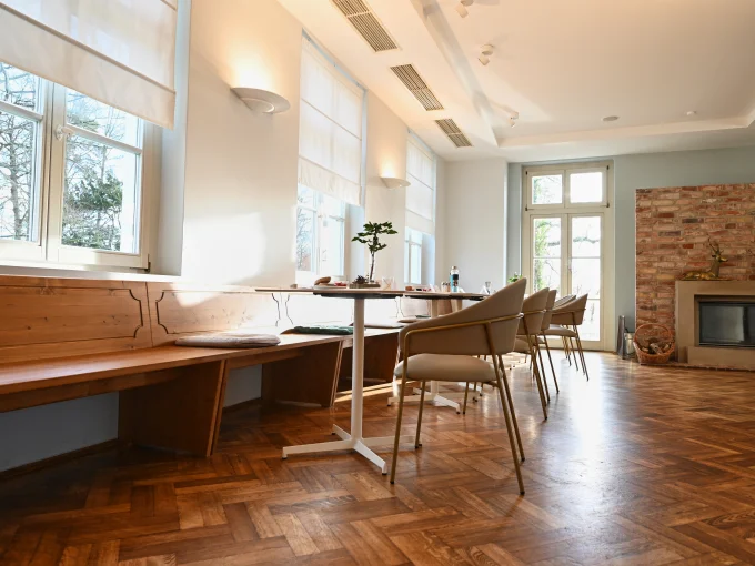 Tische in einer gemütlichen Speiselounge, umgeben von einladenden Stühlen und warmem Licht.