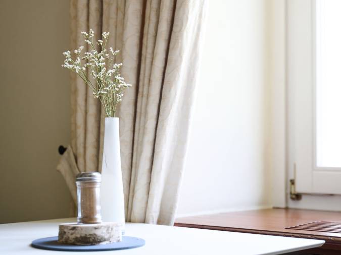 Ruhiger, hell gestalteter Raum mit Vase am Fenster